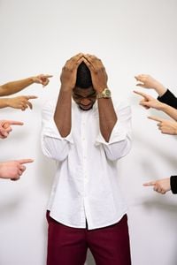 Homme frustré et stressé, pointé du doigt par plusieurs mains accusatrices.